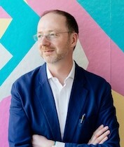 Headshot of Moderator Gareth Doherty against a colorful wall