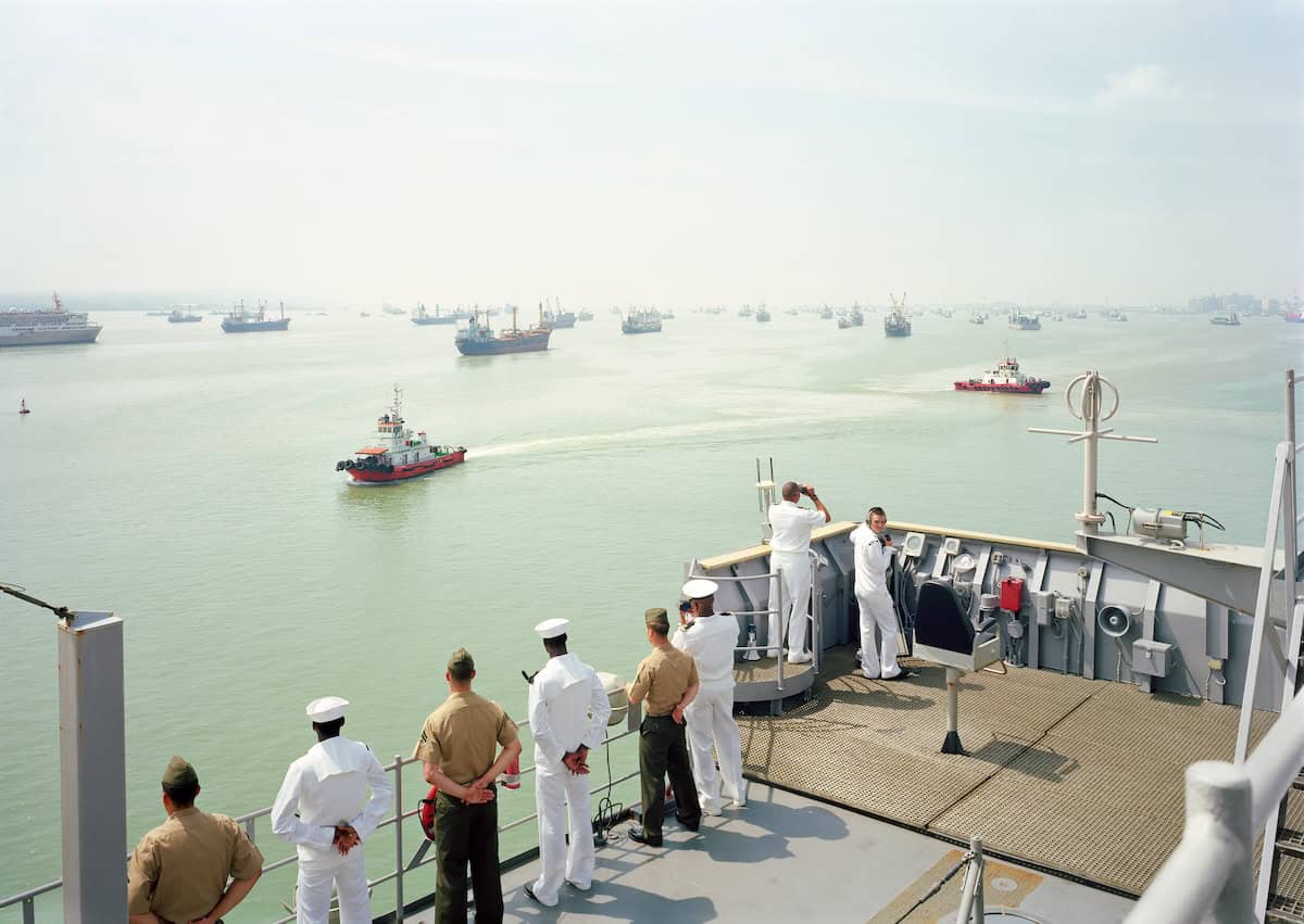 Marines on a navy ship looking out onto the ocean.