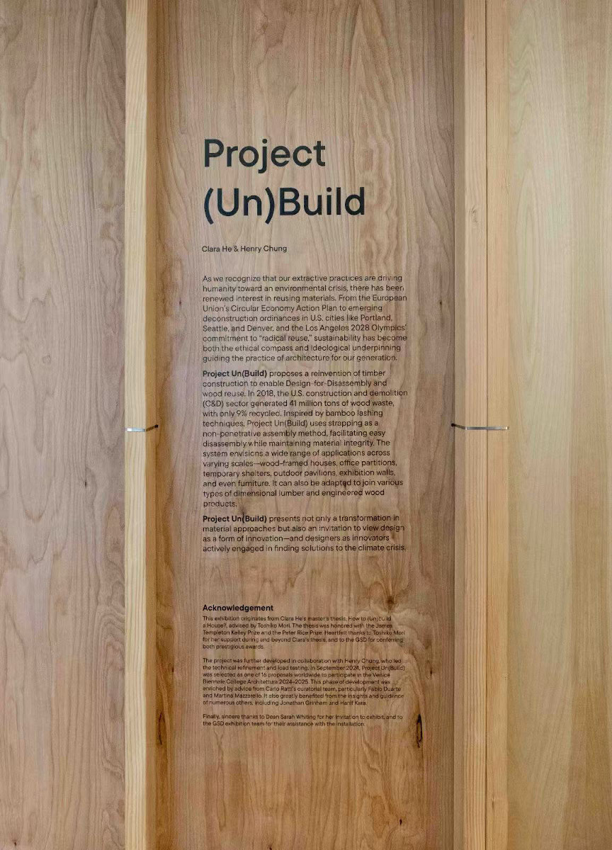 Detail of the exhibit showing an introductory text panel on a wooden wall between vertical framing studs.