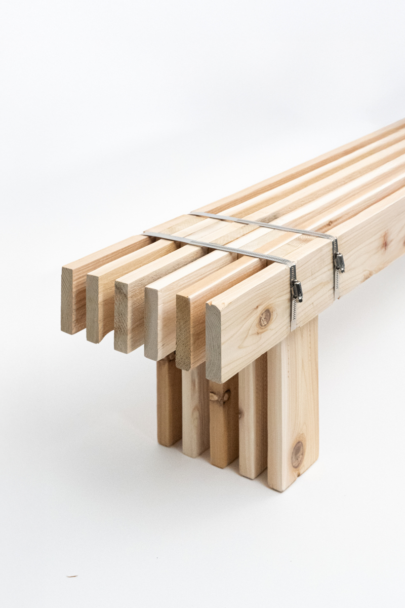 A seating bench built with multiple slats of wood joined together with long steel adjustable straps.