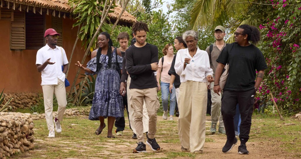 A group of students and faculty walk through a garden path in Ghana.