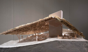 Model of a building with a thatched roof and human figures inside