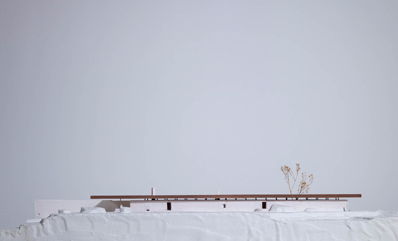A white model of terraced terrain with a building in the middle