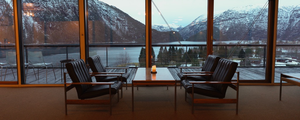 table and chairs against a glass wall overlooking lake and mountains