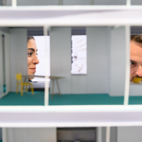 A detail of an architectural model with two people viewing it.