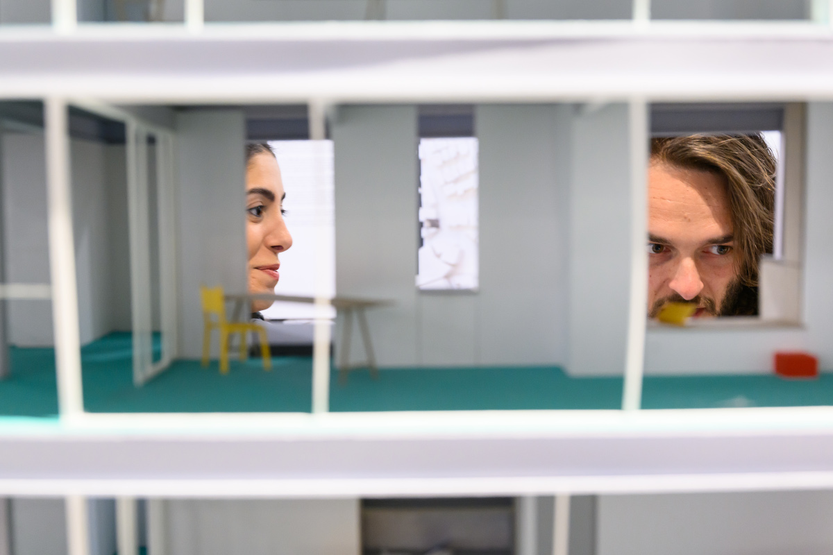 A detail of an architectural model with two people viewing it.