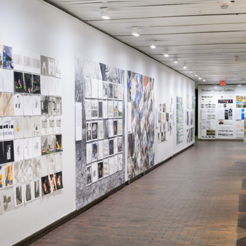 A view of the exhibit in Druker Design Gallery showing walls with a variety of 2D images displayed along it.