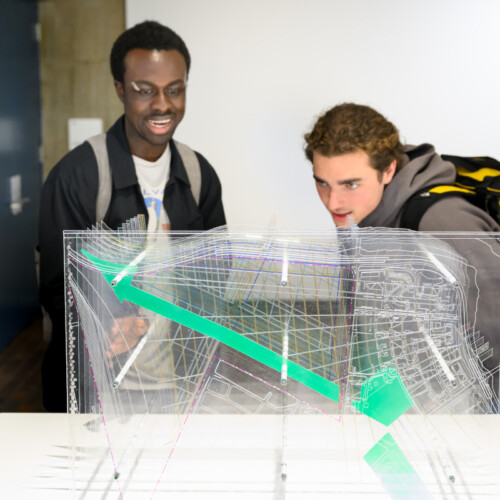 Two people viewing a model made of layers of acrylic.