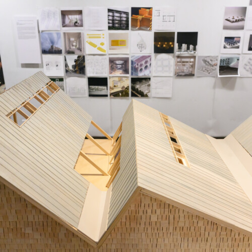 Detail of a wooden architectural model showing a roof with multiple angles.