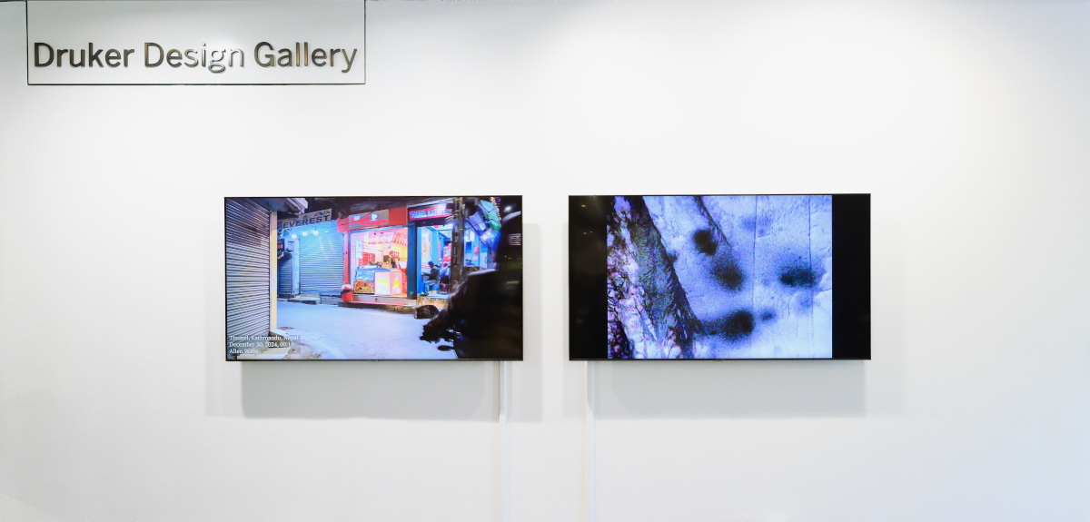 A wall in Druker Design Gallery displaying two large video screens with colorful imagery.