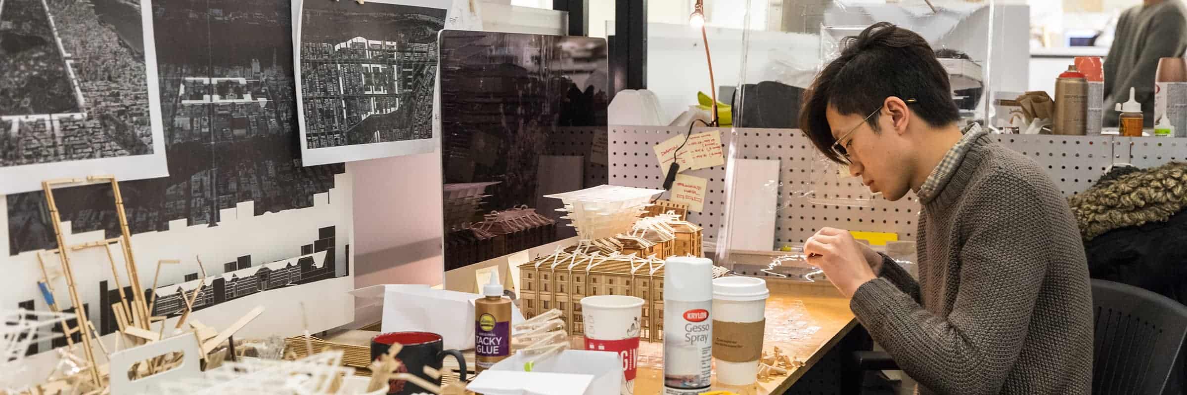 Student at desk working on architecture project.