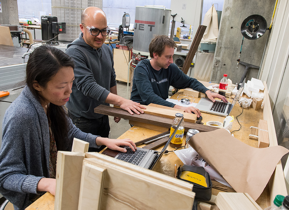 Students in the Fab Lab at a work table surrounded by tools and wood.