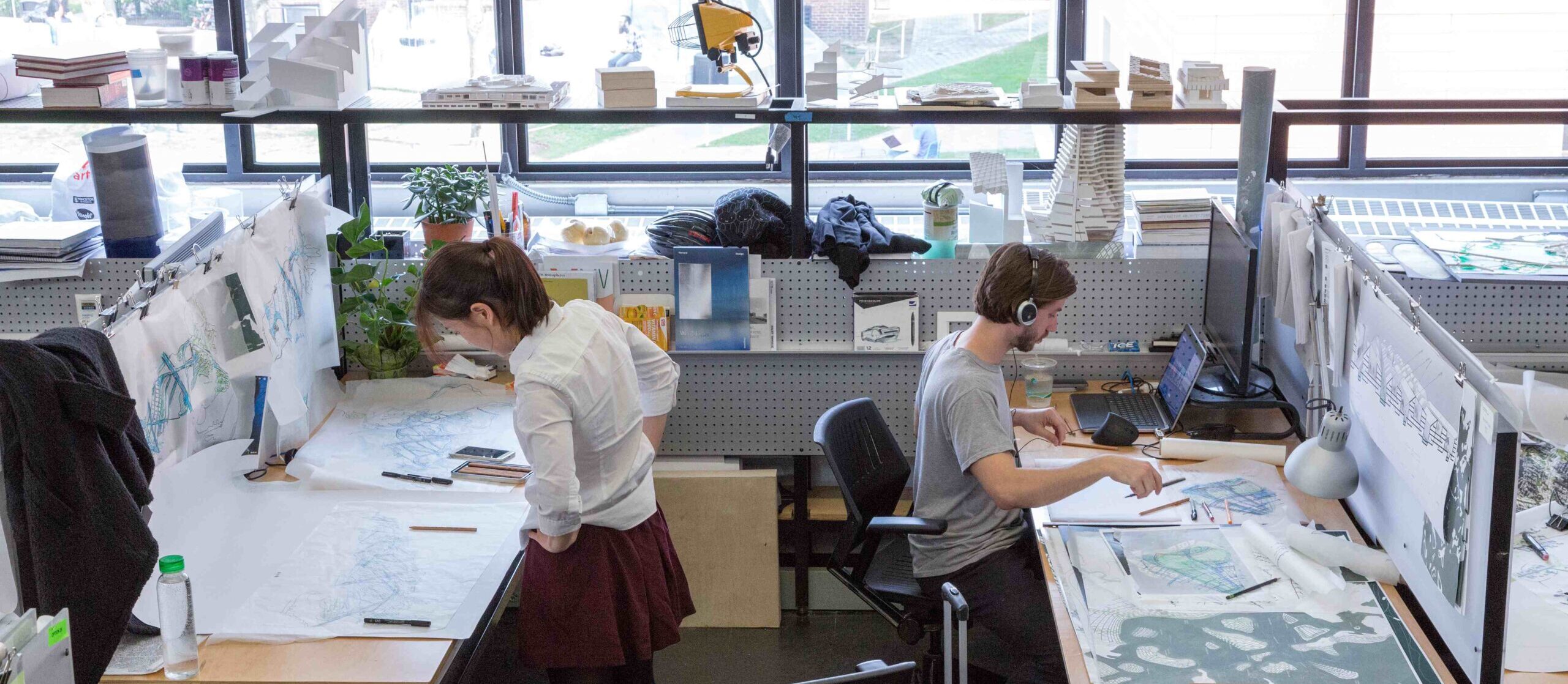 Two students work at their desks in the Gund Hall trays.