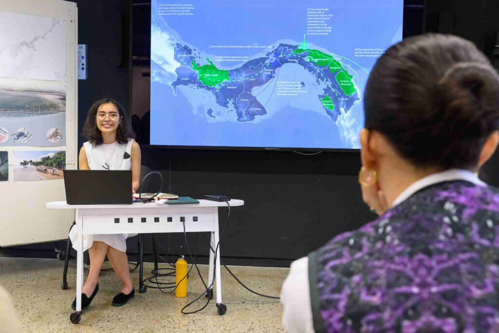 A student sits behind a laptop with a map of Panama projected on the wall behind them.