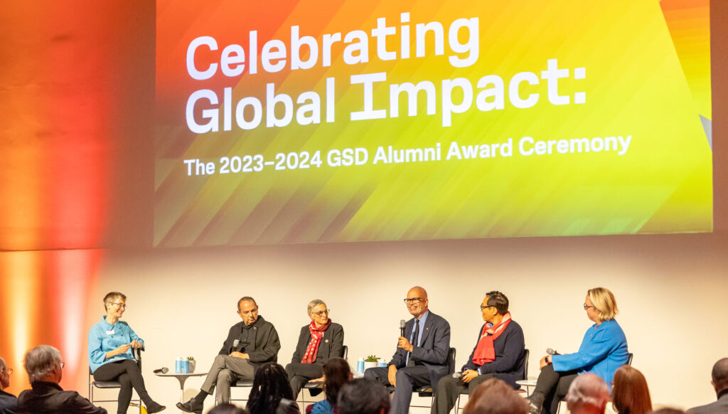 A panel on stage with 5 alumni speakers and a moderator