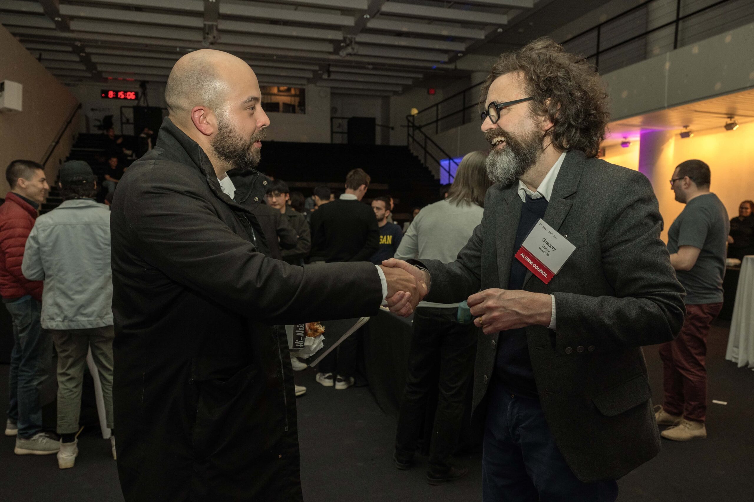 Two alumni shake hands in Piper Auditorium