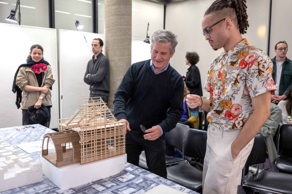 A faculty member and a student examine an architectural model together