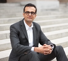 Headshot of Ali Malkawi seated on marble steps with his hands clasped.