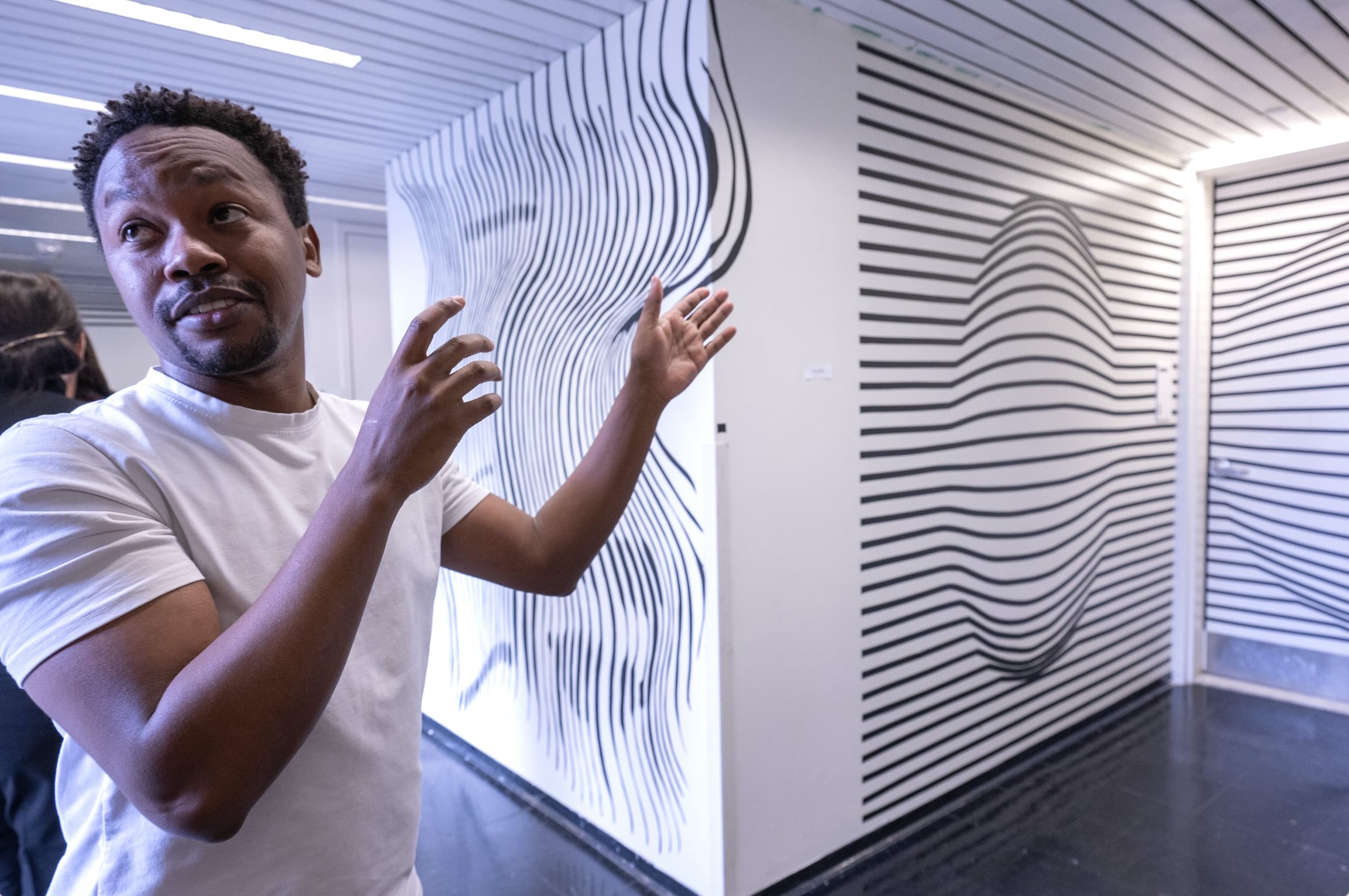 student stands in hallway with walls striped in black and white optical illusions