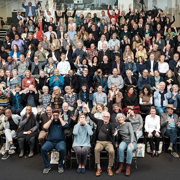 Large group photo of many people in an assembly hall.