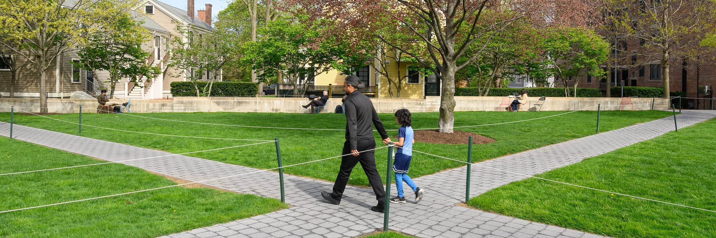 Outdoor courtyard with a man and child walking down the path.
