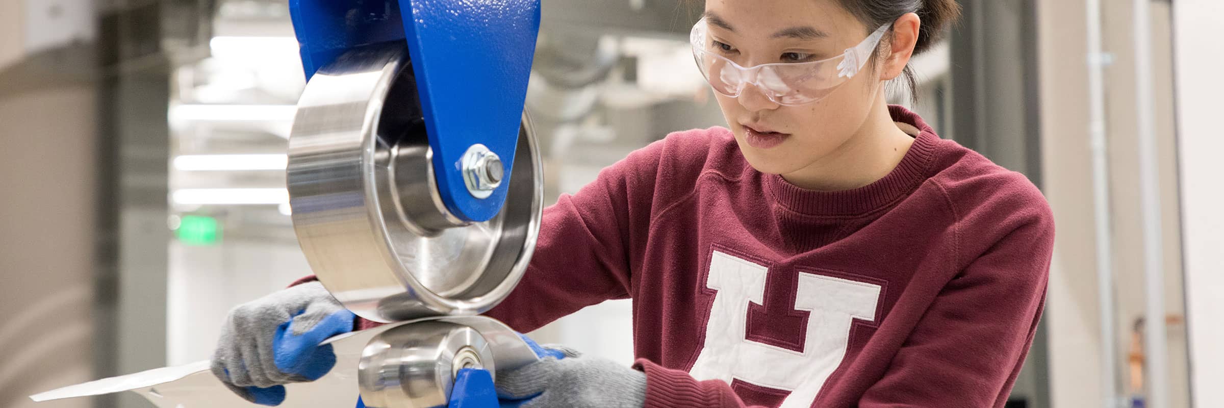 Student working with heavy machinery and wearing protective glasses.