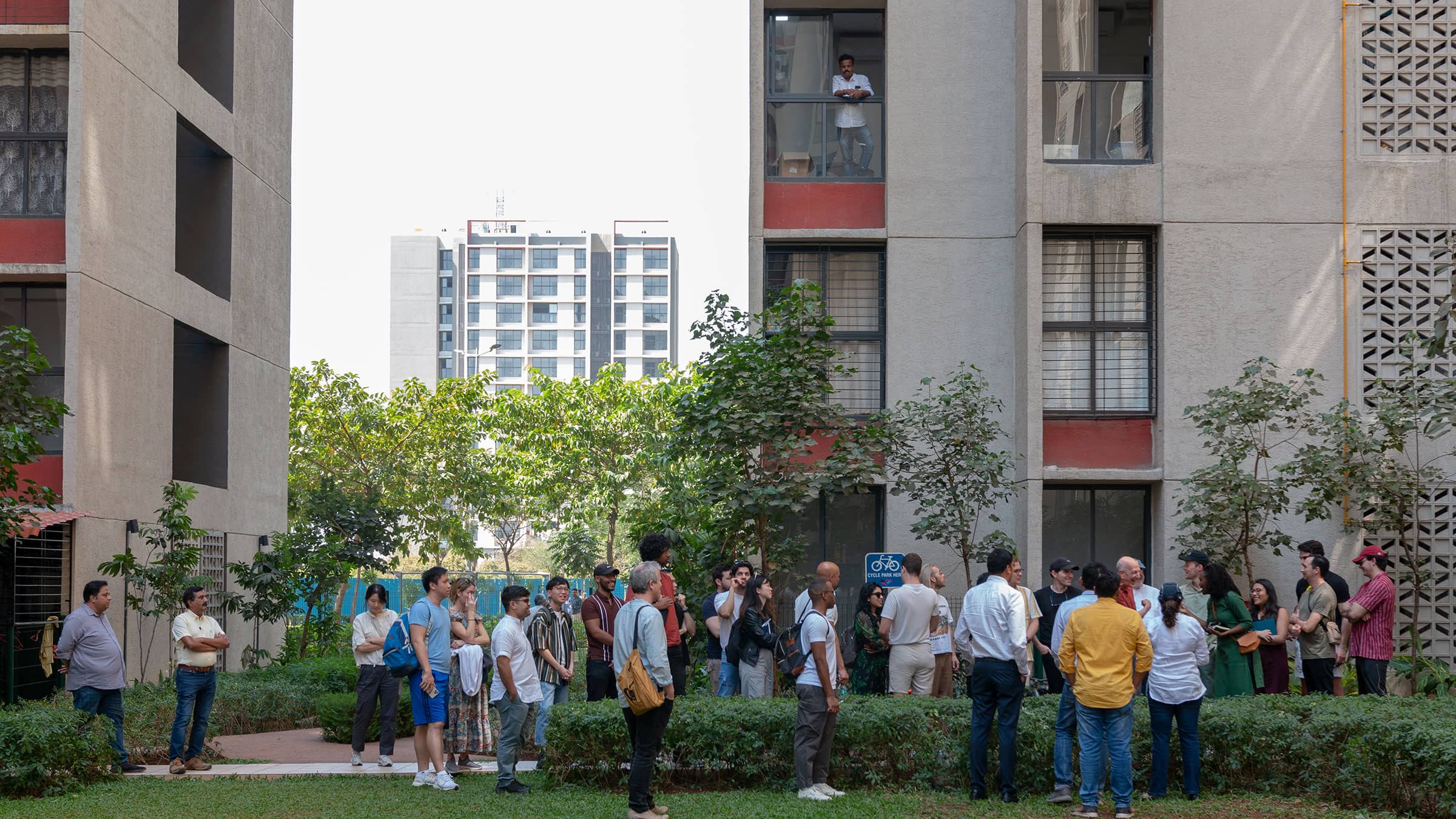 A group of people standing and talking in a city courtyard surrounded by residential buildings.