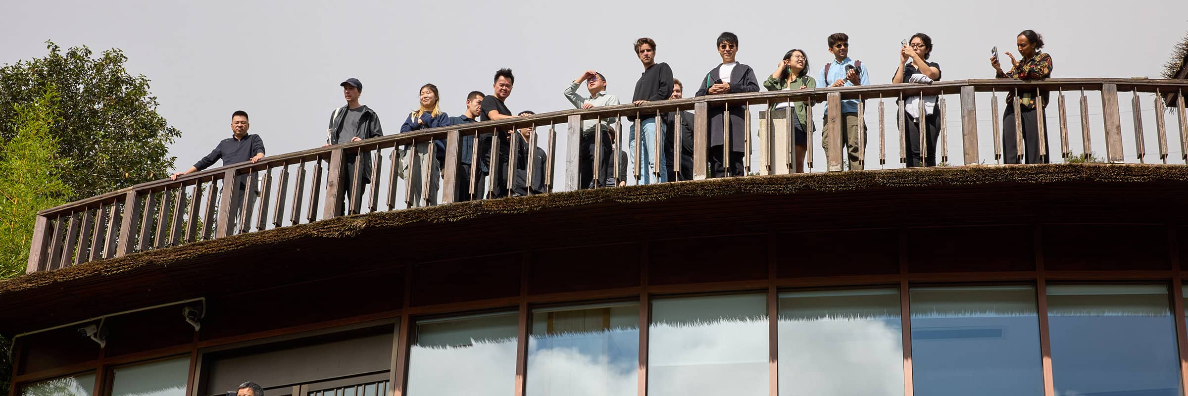 Student group on a trip standing behind a railing on the roof of a building.