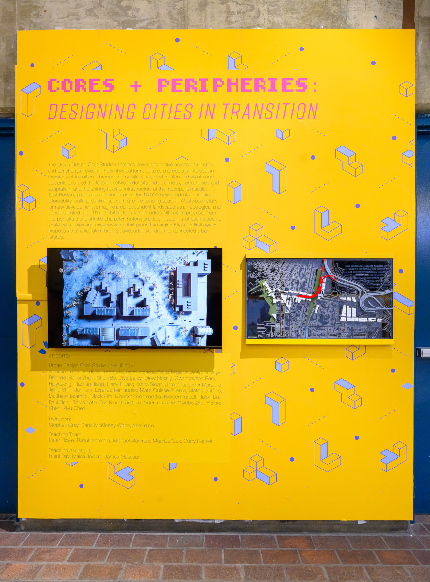 A yellow wall displaying a video screen and an architectural model.