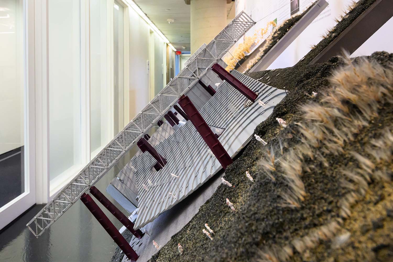 Close up of the tilted model showing tiny figures under a hanging pergola just beyond a grassy hill.