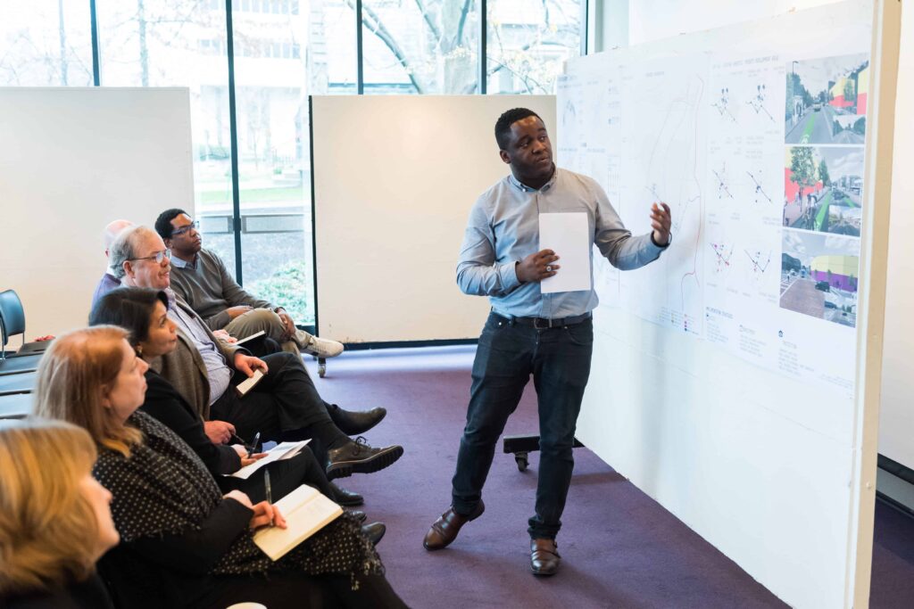Student presenting in front of a group of critics during studio reviews.