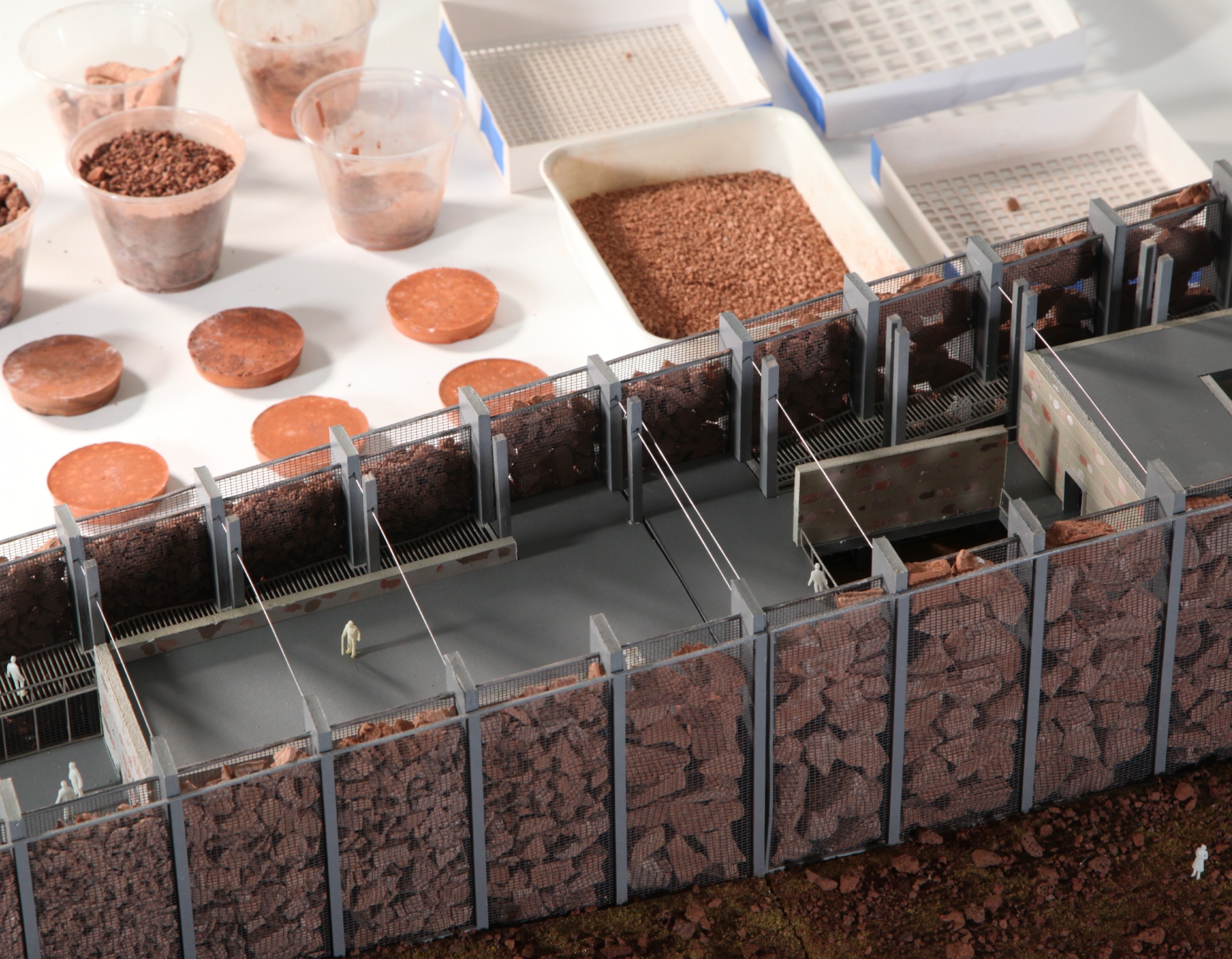 Architectural model of public walkway with walls constructed of red rocks, backgrounded by red rock in various forms.
