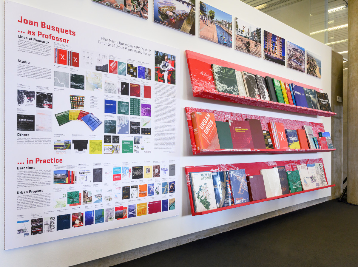 A white wall with images, text, and red bookshelves displaying books.