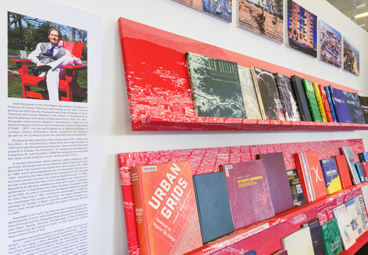 A white wall with images, text, and red bookshelves displaying books.