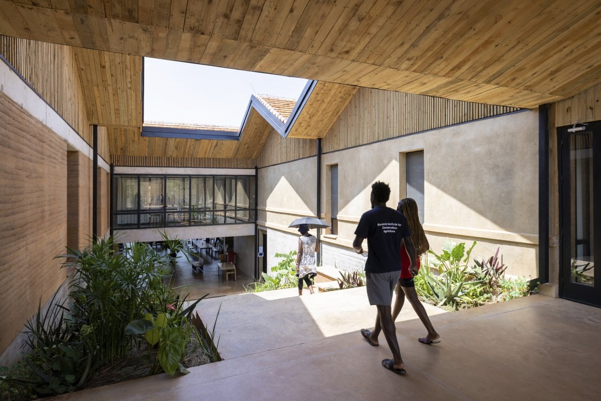Several people walk into an open-air courtyard in a building on the RICA Campus