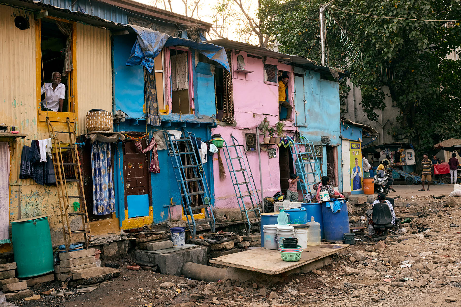 Informal houses along a street with people doing daily chores in Mumbai
