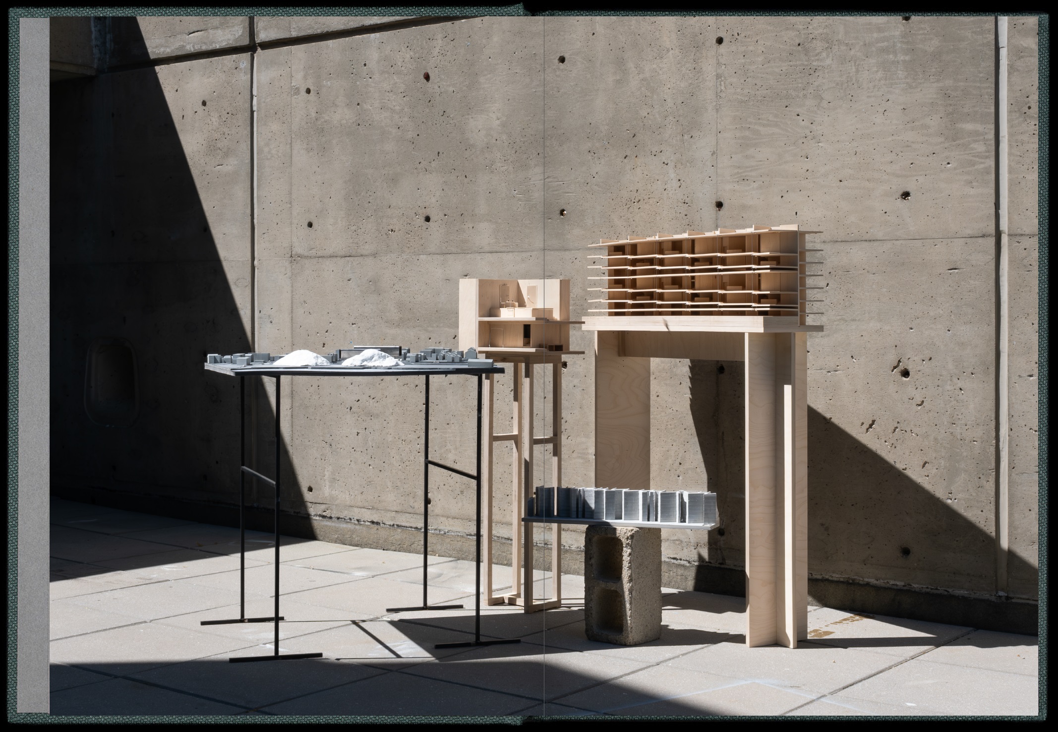 Architectural models on platforms against concrete wall background.