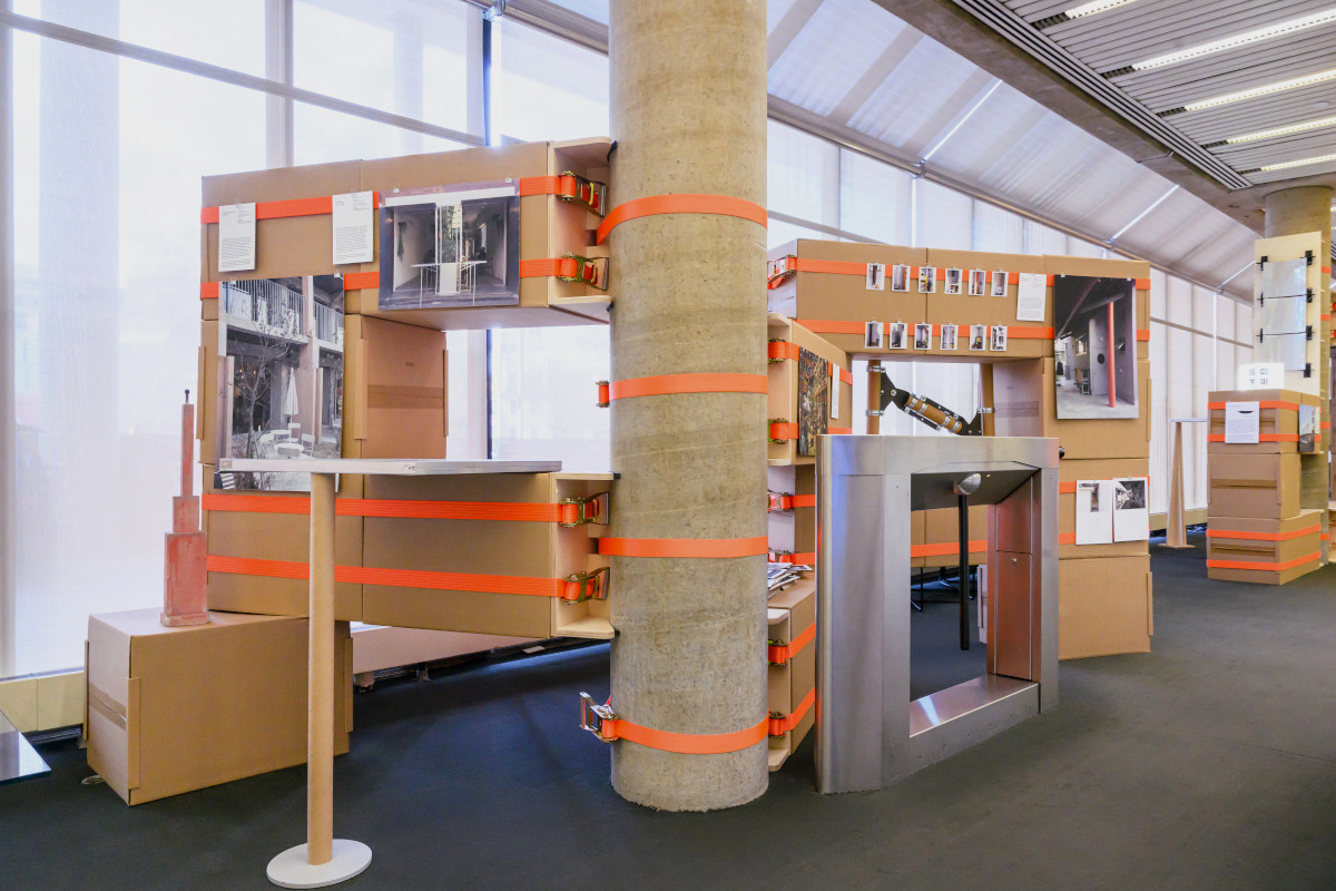 A temporary structure made of cardboard boxes strapped to a concrete column.
