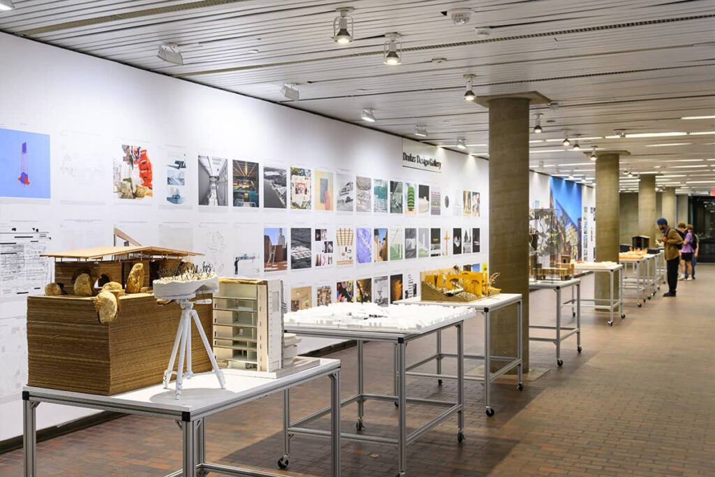 Exhibition hall with people looking at student work.