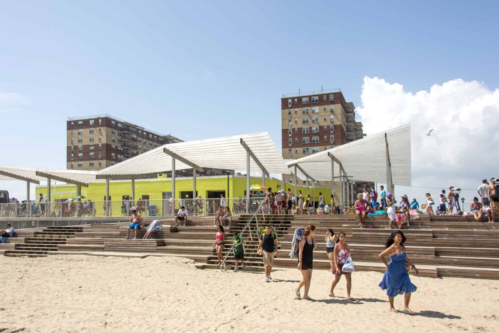 Crowds gather on a sunny day on the steps of Rockaway beach