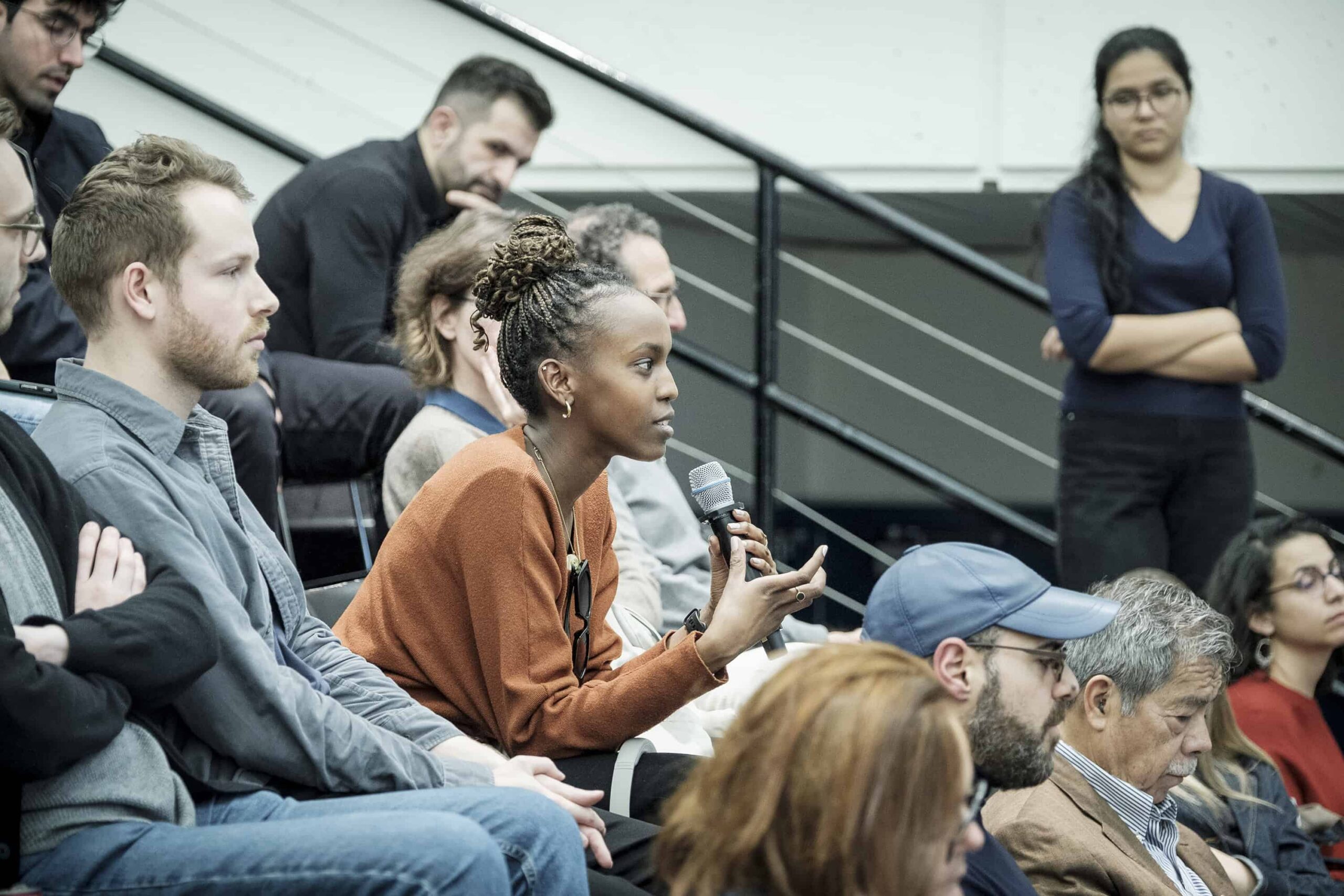 a student in an audience holds a microphone to ask a question