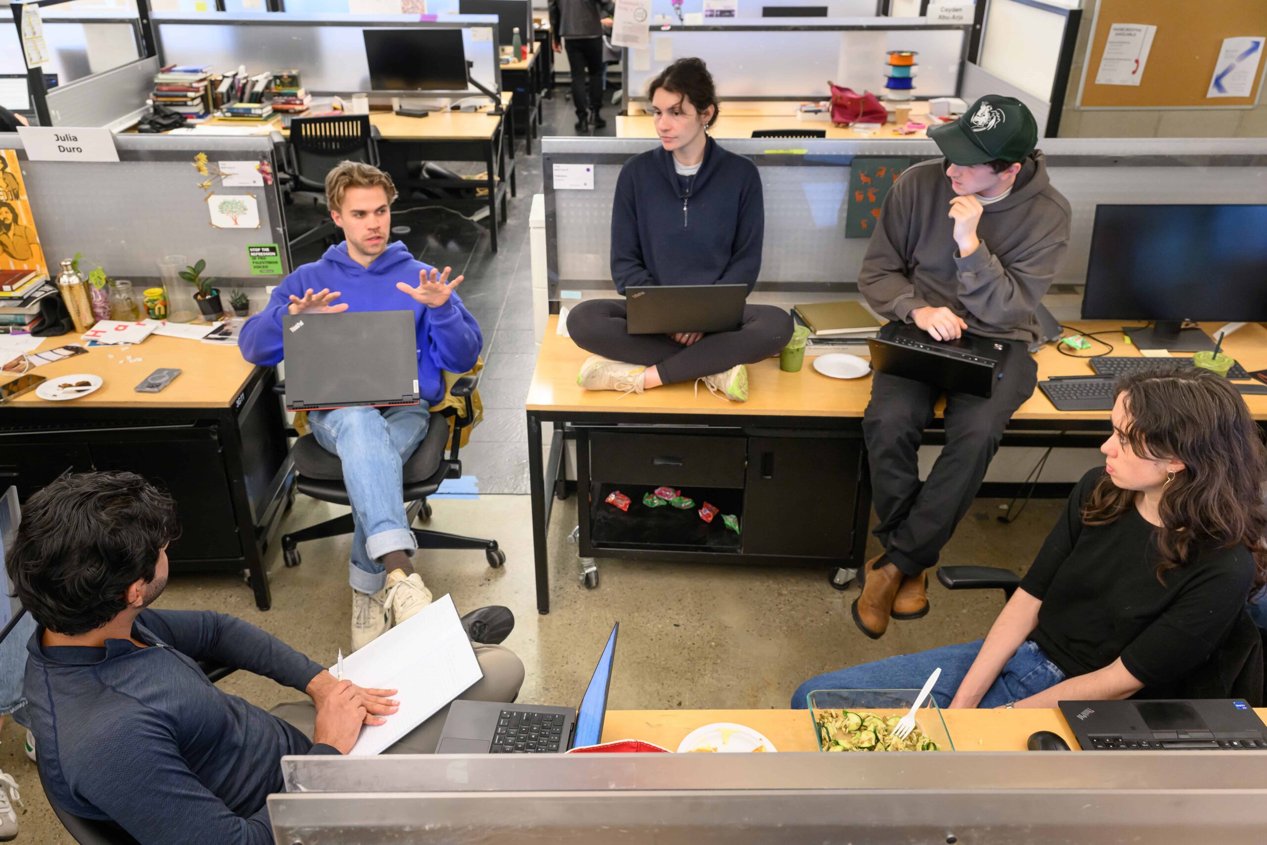 five students gathered at desks in the Trays