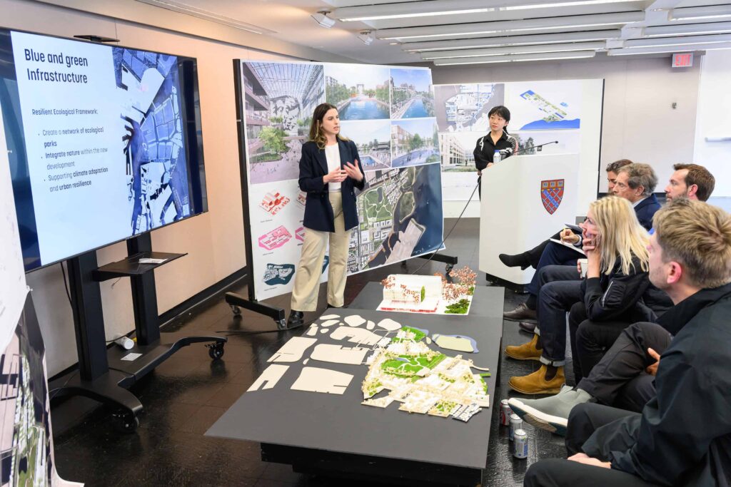 Two students present behind a podium and in from of a panel of reviewers in Dan Stubbergaard's City as Resouce studio