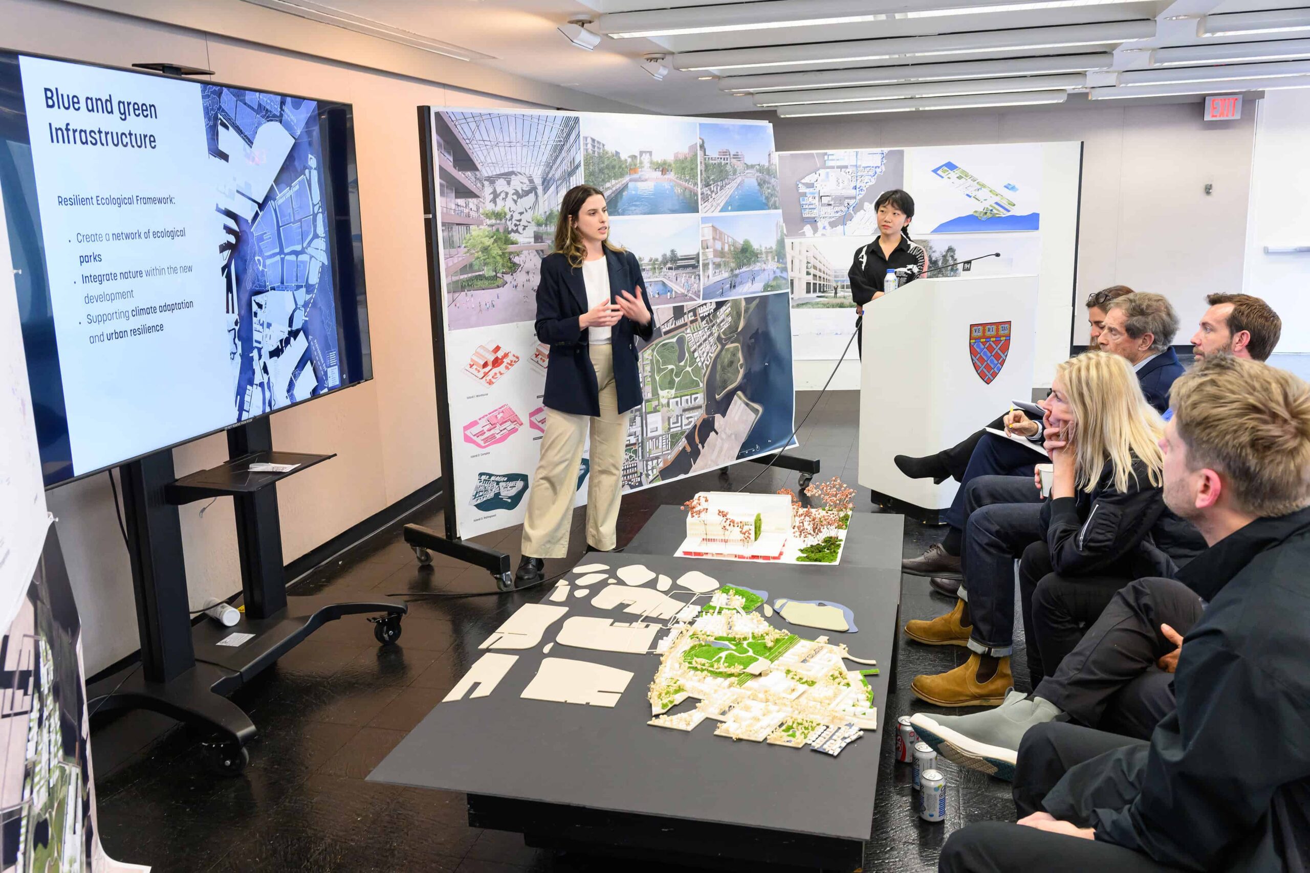 Two students present behind a podium and in from of a panel of reviewers in Dan Stubbergaard's City as Resouce studio