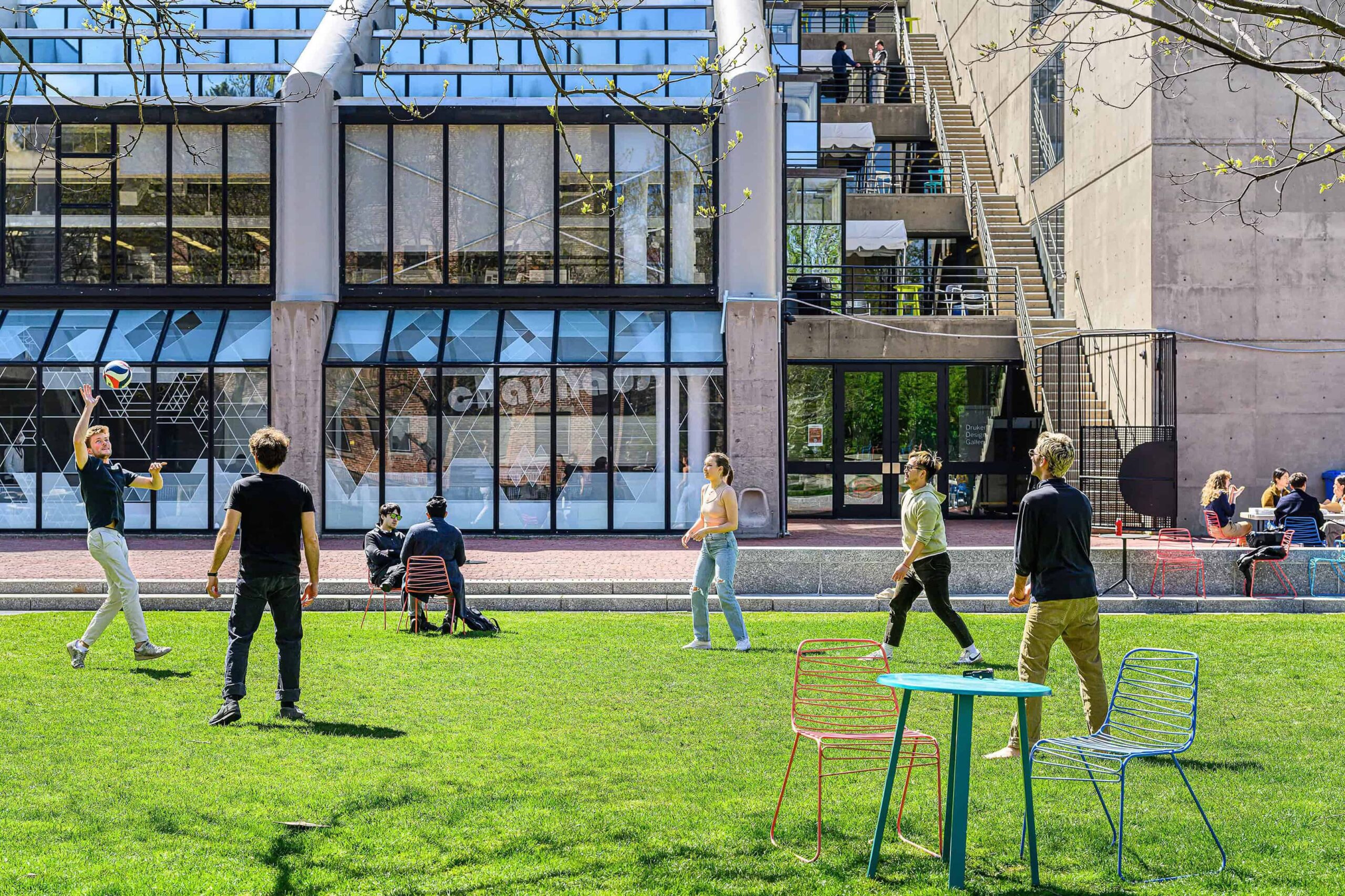 a group of students plays with a soccer ball outside behind Gund Hall