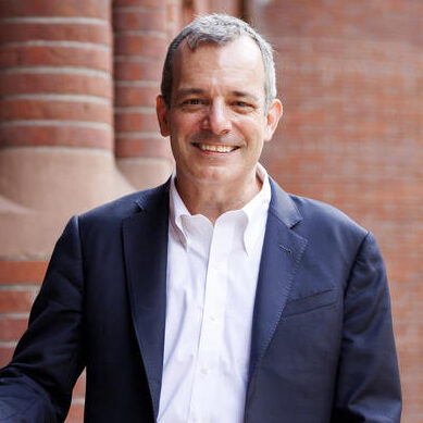 Provost John Manning smiles in front of a brick building.