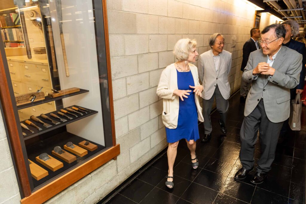 Ann Whiteside and visitors from Takenaka walk down a hallway in Gund Hall's lower level to view the donated Japanese carpentry tools