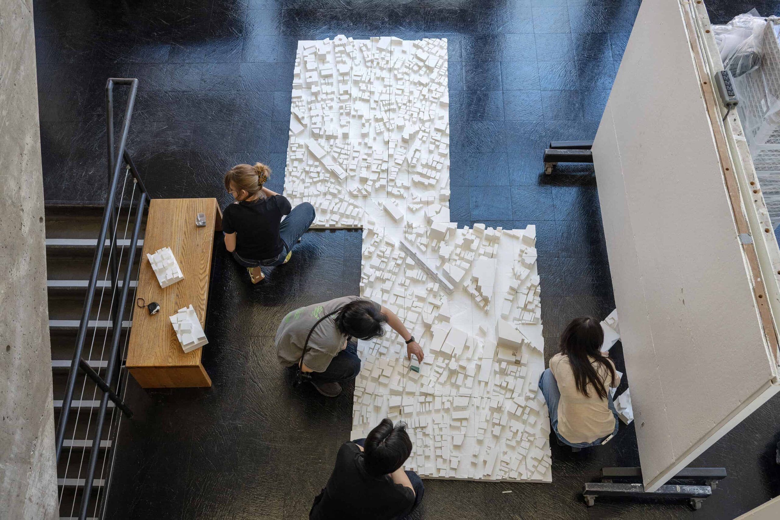 Ariel view looking down on students assembling a white architectural model on the floor