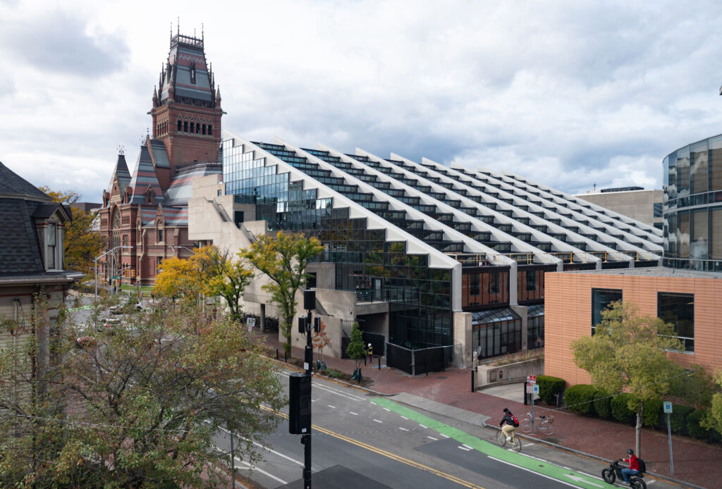 Aerial view of sloping glass and concrete building near 19th century brick hall.