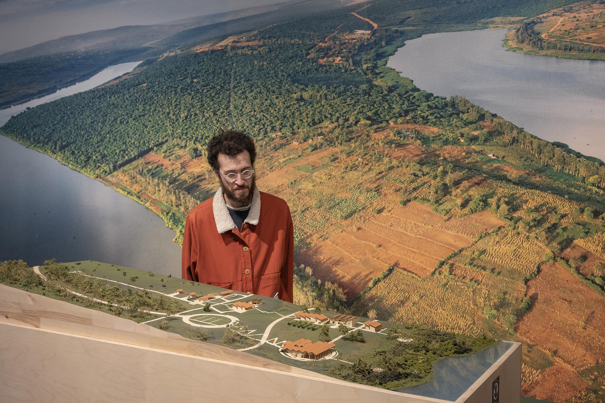 A man stands between a large aerial photo and a realistic site model.